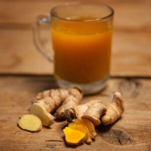 Glass of bright orange turmeric-ginger shot as another good example of what to take for gut cleanse for better digestion